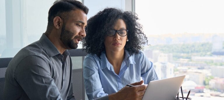 Two business professional working in front of a laptop